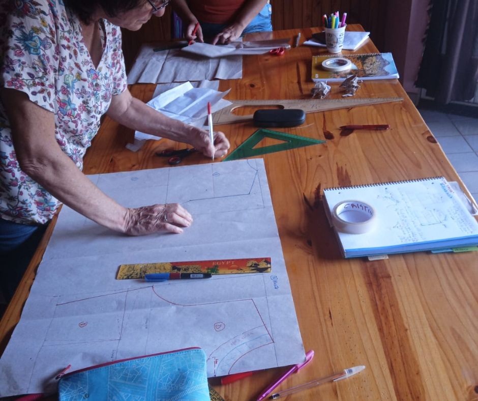 Alumnas adultas mayores trazando moldes sobre la mesa en una clase de moldería de Taftan Atelier