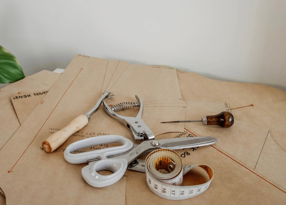 Herramientas de costura sobre moldes de papel: tijera, cinta métrica y punzón